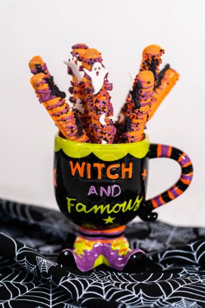 Foto de Barras de pretzel cubiertas de chocolate de Halloween con aspersiones en una taza. - Imagen libre de derechos