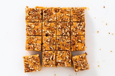 Photo for Cutting pumpkin spice fudge into square pieces on a white cutting board. - Royalty Free Image