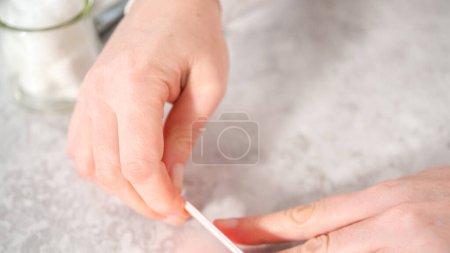 Téléchargez les photos : Femme finissant sa manucure à la maison avec des outils de manucure simples. Clous de classement avec un filtre à ongles. - en image libre de droit