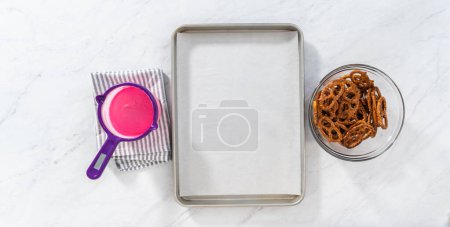 Téléchargez les photos : Flat lay. Dipping pretzels twists into melted chocolate to make chocolate-covered pretzel twists. - en image libre de droit