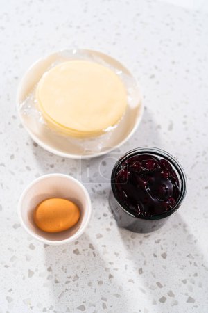 Téléchargez les photos : Ingrédients mesurés dans des bols à mélanger en verre pour faire des empanadas sucrées avec des bleuets. - en image libre de droit