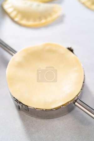 Téléchargez les photos : Remplissage de pâte empanada avec garniture tarte aux myrtilles pour faire des empanadas sucrés aux myrtilles. - en image libre de droit