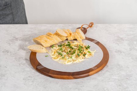 Téléchargez les photos : Assemblage d'une planche à beurre avec légumes et pain sur une planche à découper ronde en bois. - en image libre de droit