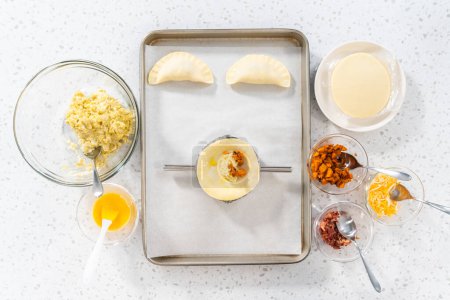 Photo for Flat lay. Filling empanada dough with egg filling to make breakfast empanadas with eggs and sweet potato. - Royalty Free Image