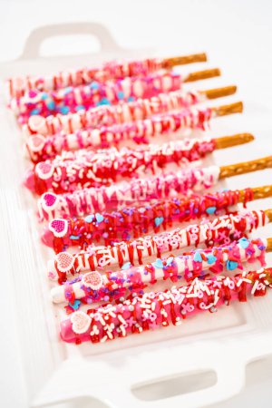 Photo for Chocolate-covered pretzel rods decorated with heart-shaped sprinkles for Valentines Day. - Royalty Free Image