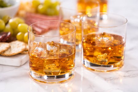 Photo for Scotch on the rocks in whiskey glass on a white marble surface. - Royalty Free Image