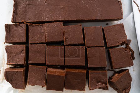 Téléchargez les photos : Couper du caramel maison en petits morceaux sur une planche à découper blanche. - en image libre de droit