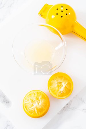 Foto de Zesting y jugo de limón fresco en una tabla de cortar blanca. - Imagen libre de derechos
