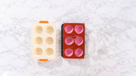 Téléchargez les photos : Enlever les coquilles de chocolat rose des moules de chocolat au silicone avec du chocolat rose fondu pour préparer des bombes au chocolat chaud. - en image libre de droit