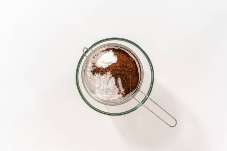 Téléchargez les photos : Pose plate. Tamisage des ingrédients par tamiseur à main pour faire maison mélange de chocolat chaud. - en image libre de droit