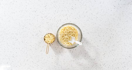 Photo for Flat lay. White chocolate chips in a glass mixing bowl. - Royalty Free Image