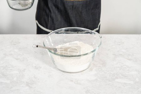 Photo for Mixing ingredients in a glass mixing bowl to prepare coconut banana pancakes. - Royalty Free Image