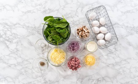 Téléchargez les photos : Pose plate. Ingrédients dans des bols à mélanger en verre pour préparer des frittata aux épinards et au jambon. - en image libre de droit