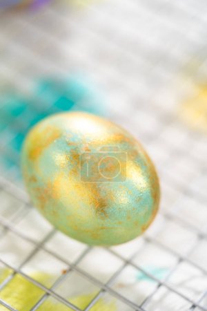 Photo for Easter egg coloring. Painting Easter eggs with gold luster. - Royalty Free Image