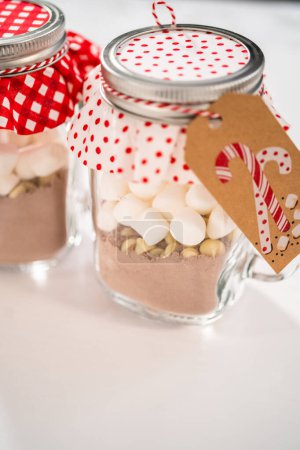 Foto de Hacer mezcla casera de chocolate caliente en tarro de albañil para regalo de comida de Navidad. - Imagen libre de derechos