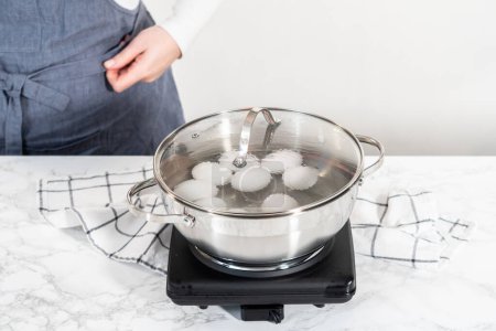 Photo for Boiling white eggs in a cooking pot to prepare hard-boiled eggs. - Royalty Free Image