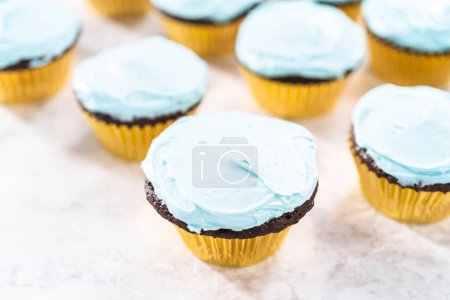 Téléchargez les photos : Décorer des cupcakes au chocolat avec glaçage à la crème au beurre et bonbons arc-en-ciel. - en image libre de droit