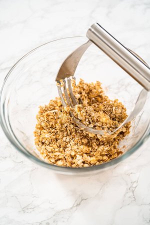 Photo for Mixing ingredients in a large glass mixing bowl to bake banana oatmeal muffins. - Royalty Free Image