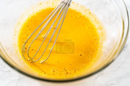 Photo for Lemon wedge cookies with lemon glaze. Mixing wet ingredients in a large glass mixing bowl to bake lemon wedge cookies. - Royalty Free Image