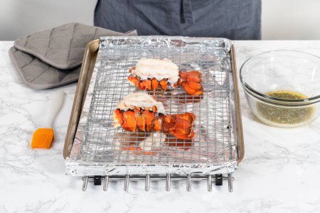 Photo for Buttering lobster tails on a baking sheet with kitchen foil. - Royalty Free Image