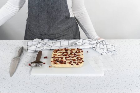 Foto de Marcando chocolate blanco dulce de nuez de arándano para cortar en trozos pequeños. - Imagen libre de derechos