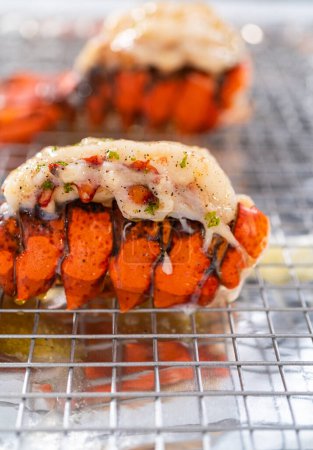 Téléchargez les photos : Beurrer les queues de homard sur une plaque de cuisson avec du papier d'aluminium de cuisine. - en image libre de droit