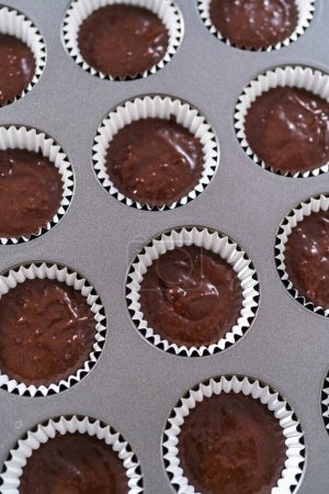 Photo for Scooping chocolate cupcake dough into the cupcake liners. - Royalty Free Image