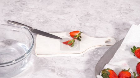 Photo for Step by step. Slicing fresh organic strawberries on a white cutting board. - Royalty Free Image