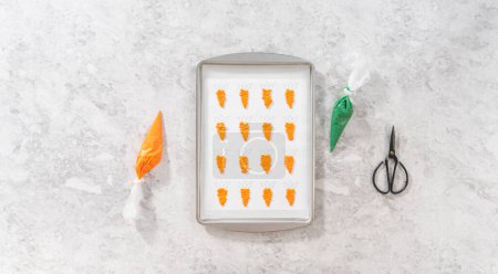 Photo for Flat lay. Piping melted chocolate from a piping bag over the parchment paper to make chocolate carrot cake toppers. - Royalty Free Image