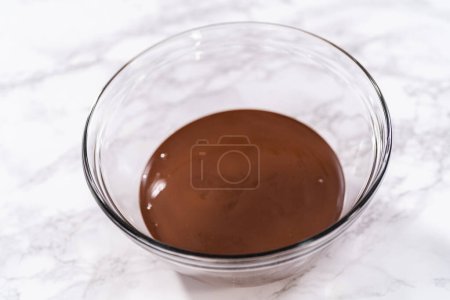 Photo for Melted chocolate in a glass mixing bowl to prepare chocolate-covered strawberries. - Royalty Free Image