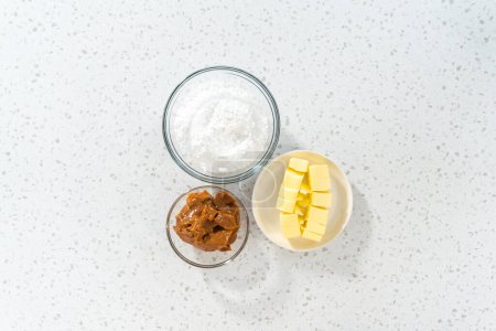 Foto de Acostado. Ingredientes medidos en cuencos de vidrio para hacer glaseado de crema de mantequilla dulce de leche. - Imagen libre de derechos