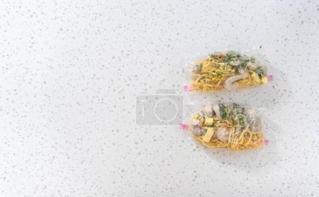 Photo for Flat lay. Packaging homemade frozen shrimp scampi meal prep into plastic resealable bags. - Royalty Free Image