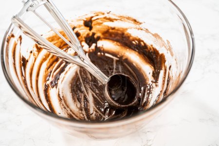 Téléchargez les photos : Scooping pâte à gâteau avec cuillère à pâte dans des doublures de papier d'aluminium cupcake pour cuire des cupcakes à la menthe poivrée au chocolat. - en image libre de droit