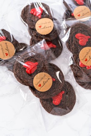 Téléchargez les photos : Biscuits au chocolat avec des cœurs de chocolat pour la Saint-Valentin emballés dans des sacs-cadeaux en plastique. - en image libre de droit