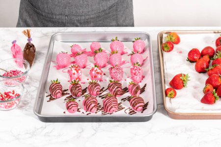 Téléchargez les photos : Décorer les fraises recouvertes de chocolat avec des bruines de chocolat et saupoudrer. - en image libre de droit