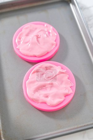Foto de Preparación de arcos de chocolate rosa para decorar galletas de shortbread en forma de panda. - Imagen libre de derechos