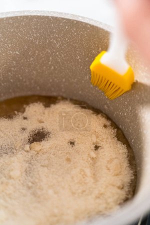 Téléchargez les photos : Sucre caramélisant dans une casserole pour faire des garnitures de cupcake au caramel. - en image libre de droit