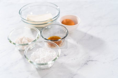 Téléchargez les photos : Ingrédients mesurés dans des bols à mélanger en verre pour faire le remplissage de fromage à la crème. - en image libre de droit