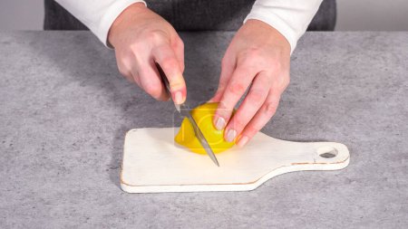 Photo for Step by step. Slicing organic lemon wedges on a white plate. - Royalty Free Image