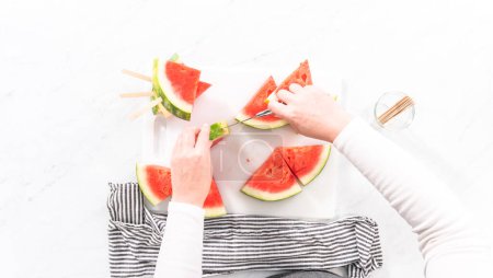 Photo for Flat lay. Slicing riped red watermelon to prepare chili lime watermelon pops. - Royalty Free Image