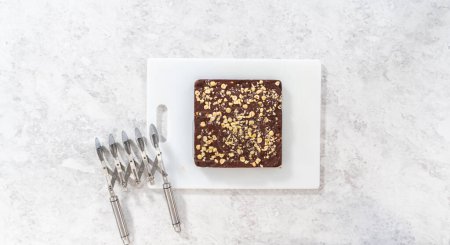 Téléchargez les photos : Pose plate. Marquage du caramel aux noisettes au chocolat à l'aide d'un coupe-pâte à roulettes pour couper en petits morceaux carrés. - en image libre de droit