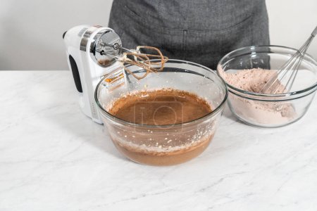 Téléchargez les photos : Mélanger les ingrédients dans un grand bol de mélange en verre pour cuire le gâteau bundt en velours rouge avec glaçage au fromage à la crème. - en image libre de droit