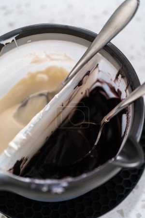 Foto de Derretir chips de chocolate en un crisol de dulces para hacer barras de pretzel cubiertas de chocolate de Halloween. - Imagen libre de derechos