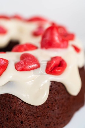 Photo for Freshly baked red velvet bundt cake with chocolate lips and hearts over cream cheese glaze for Valentines Day. - Royalty Free Image