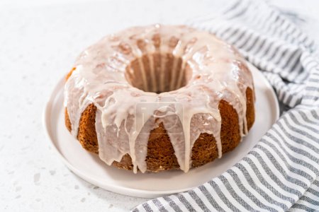 Photo for Freshly baked simple vanilla bundt cake with a white glaze on a serving plate. - Royalty Free Image