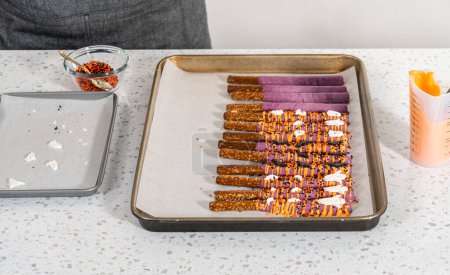 Foto de Sumergiendo barras de pretzel en chocolate derretido para hacer barras de pretzel cubiertas de chocolate de Halloween. - Imagen libre de derechos