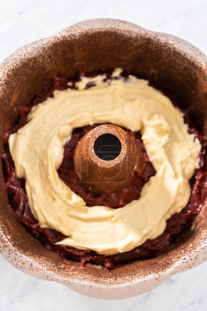 Photo for Filling metal bundt cake pan with cake butter to bake red velvet bundt cake with cream cheese glaze - Royalty Free Image