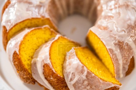 Photo for Sliced vanilla bundt cake with a white glaze on a white plate. - Royalty Free Image