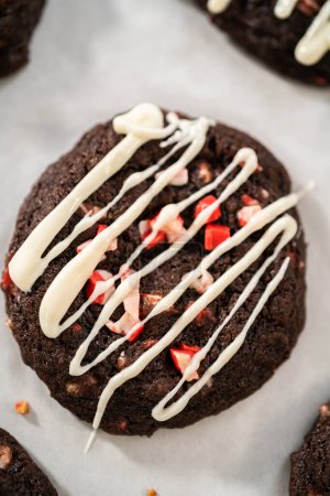 Téléchargez les photos : Biscuits au chocolat fraîchement cuits avec des copeaux de menthe poivrée et un filet de chocolat blanc sur le dessus. - en image libre de droit