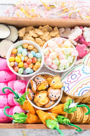 Photo for Assembling charcuterie board with Easter candies, cookies, and marshmallows. - Royalty Free Image